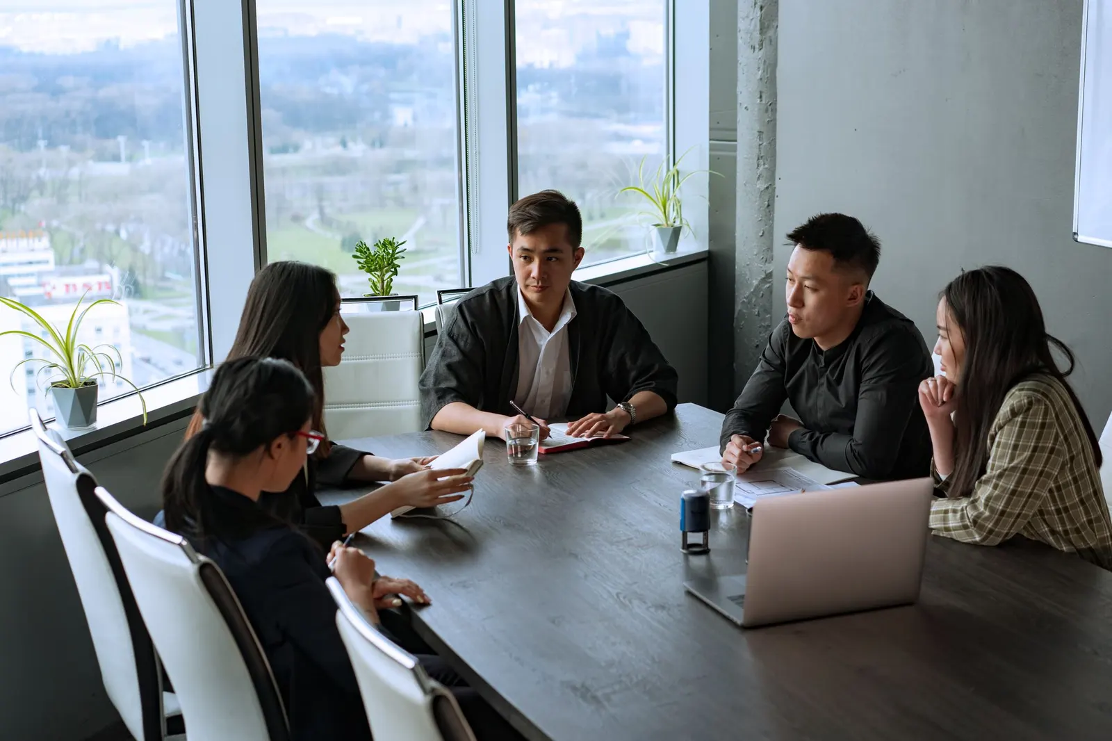 A team in discussion around a meeting table with laptops and notes