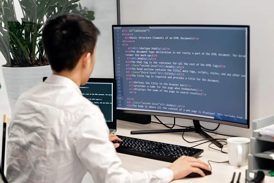 A developer writing code on a large monitor